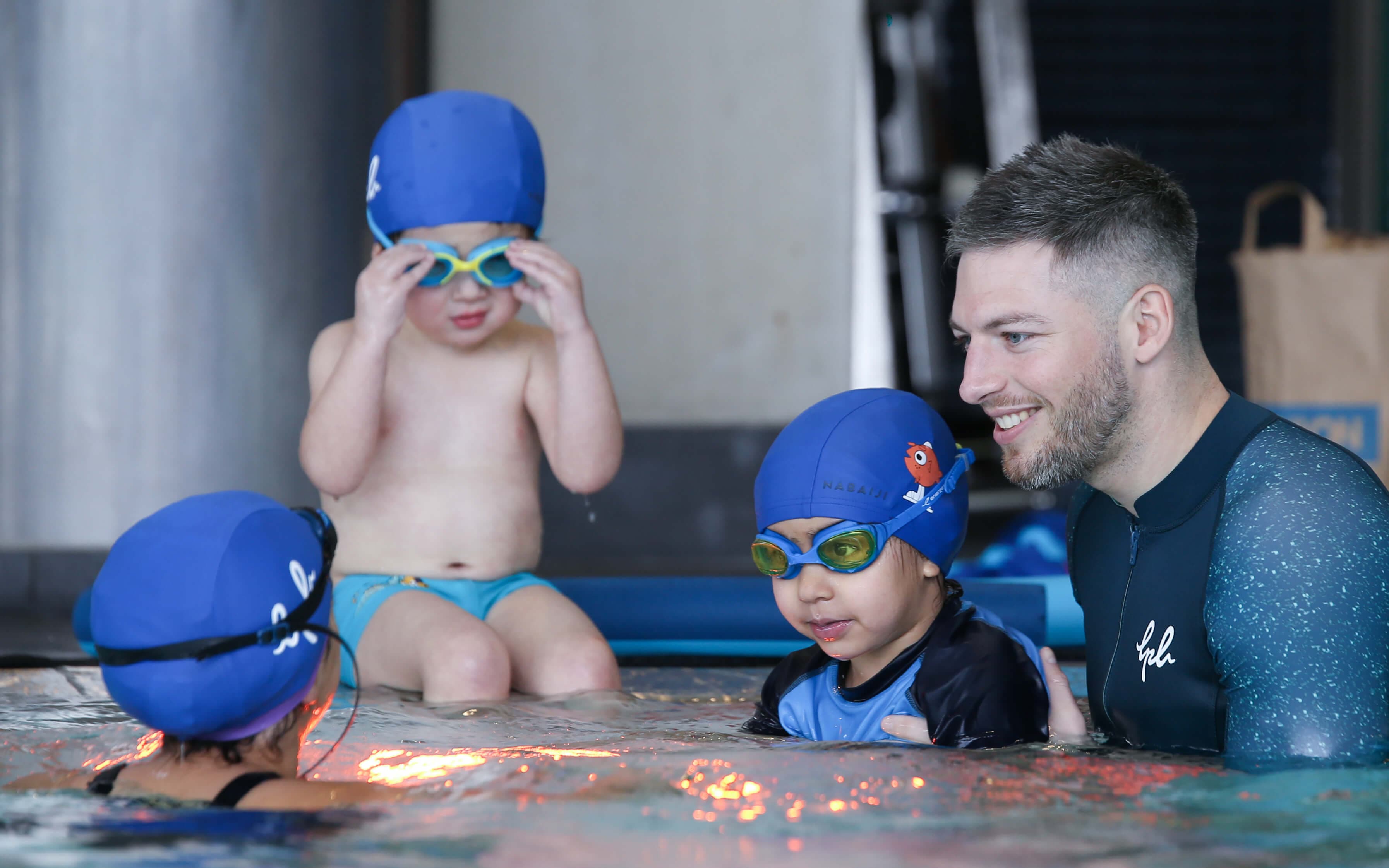 Enfant souriant dans l'eau lors d'un cours de natation